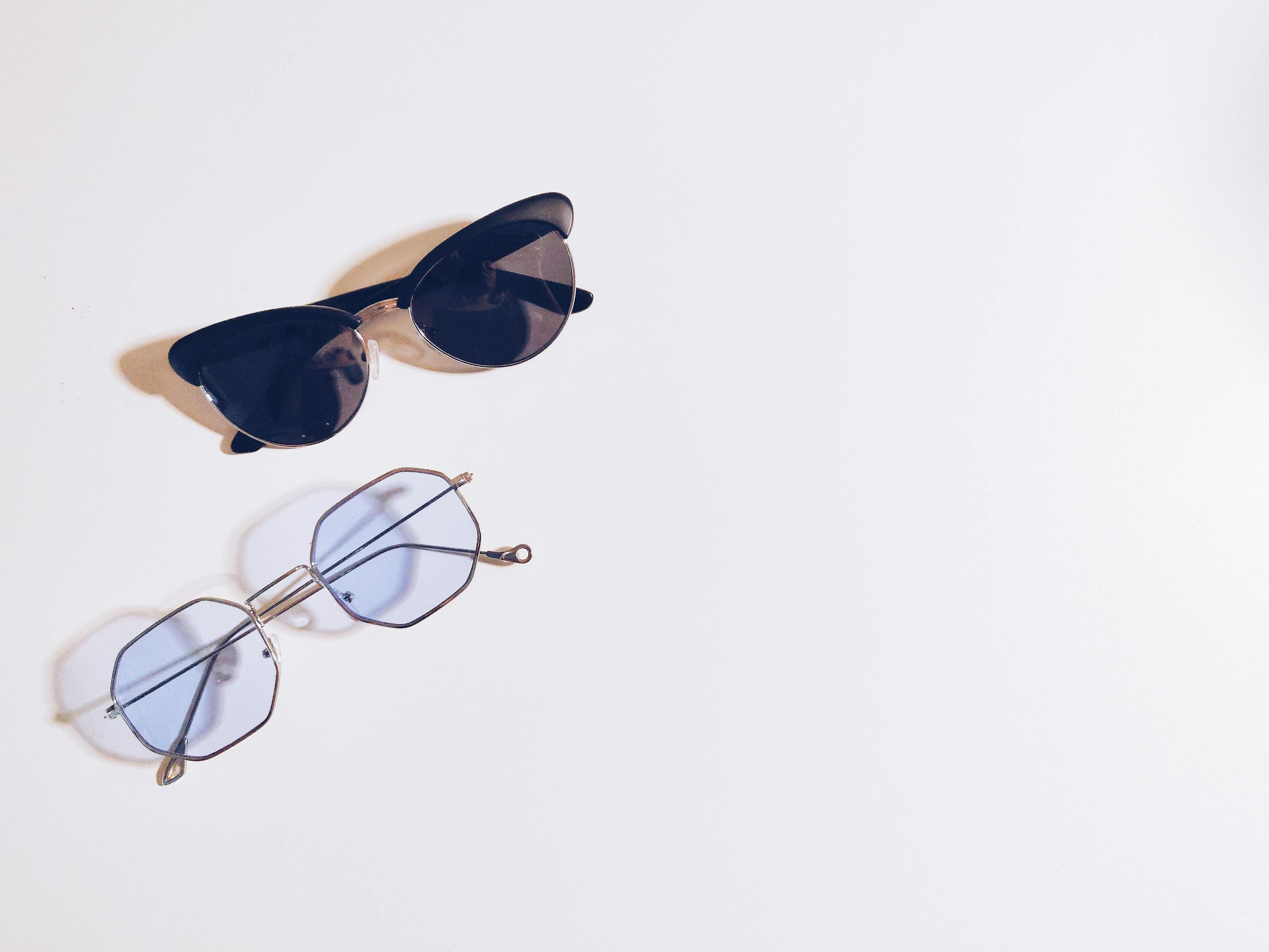 Flat lay of sunglasses and eyeglasses on a white background, perfect for fashion design concepts.