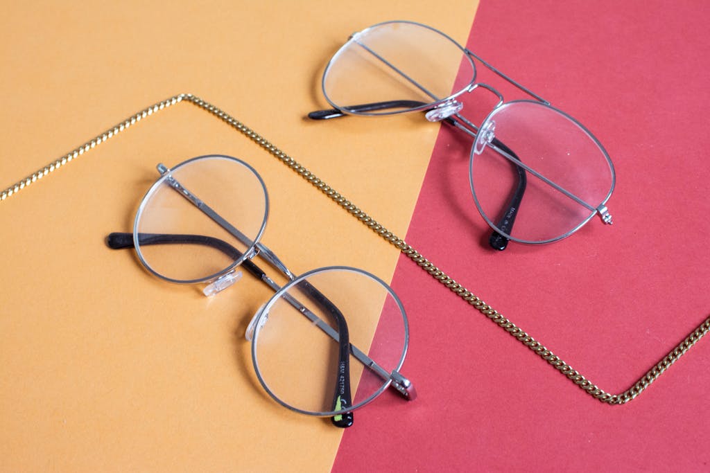 Top-down view of stylish eyeglasses on a red and yellow background.